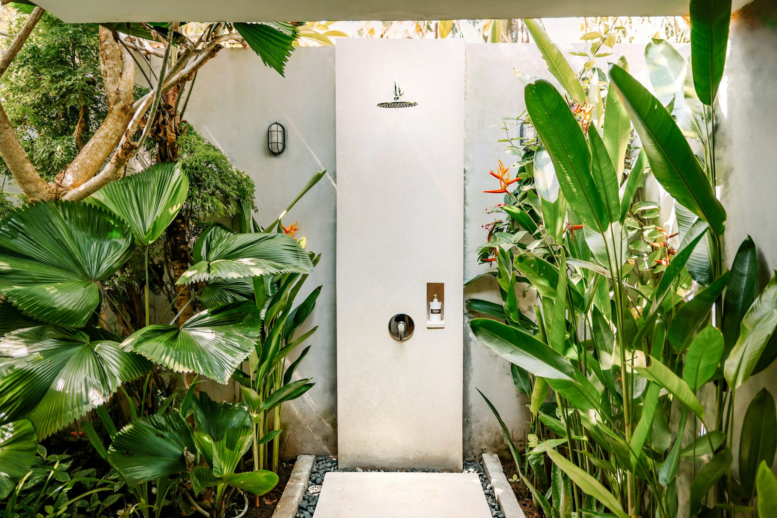 Douche extérieure en pierre entourée de plantes